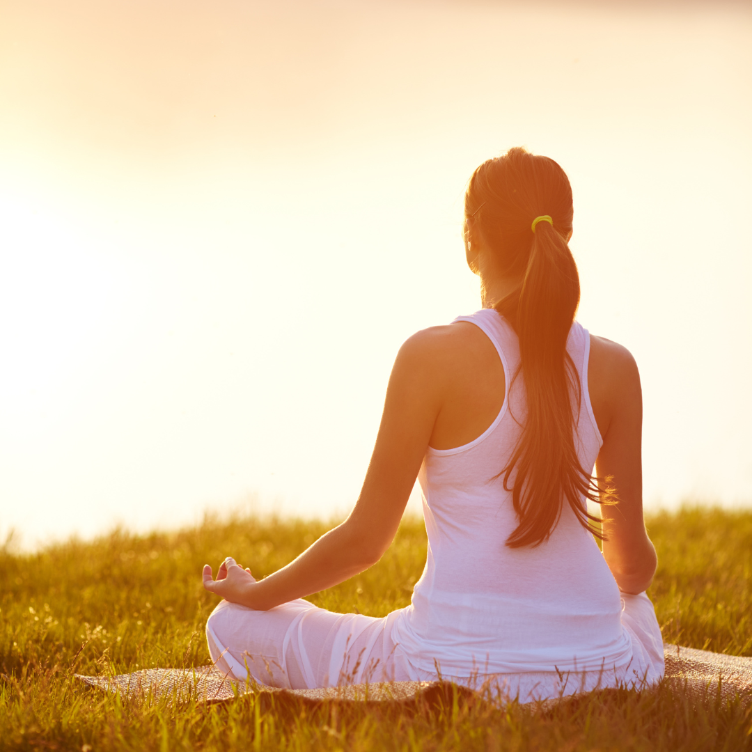 Person meditating facing the sun.